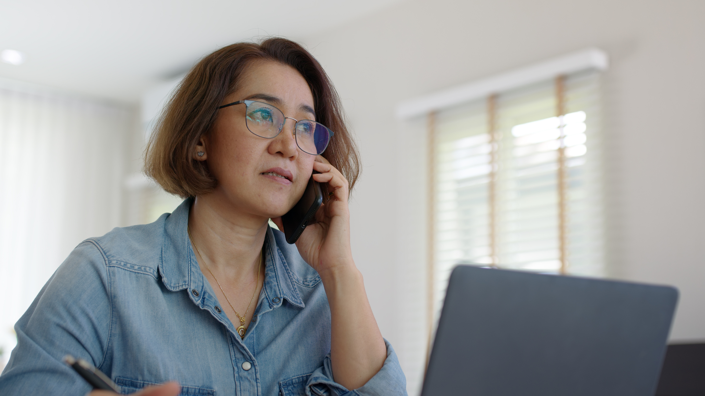 Woman sitting in front of a computer on the phone asking questions.